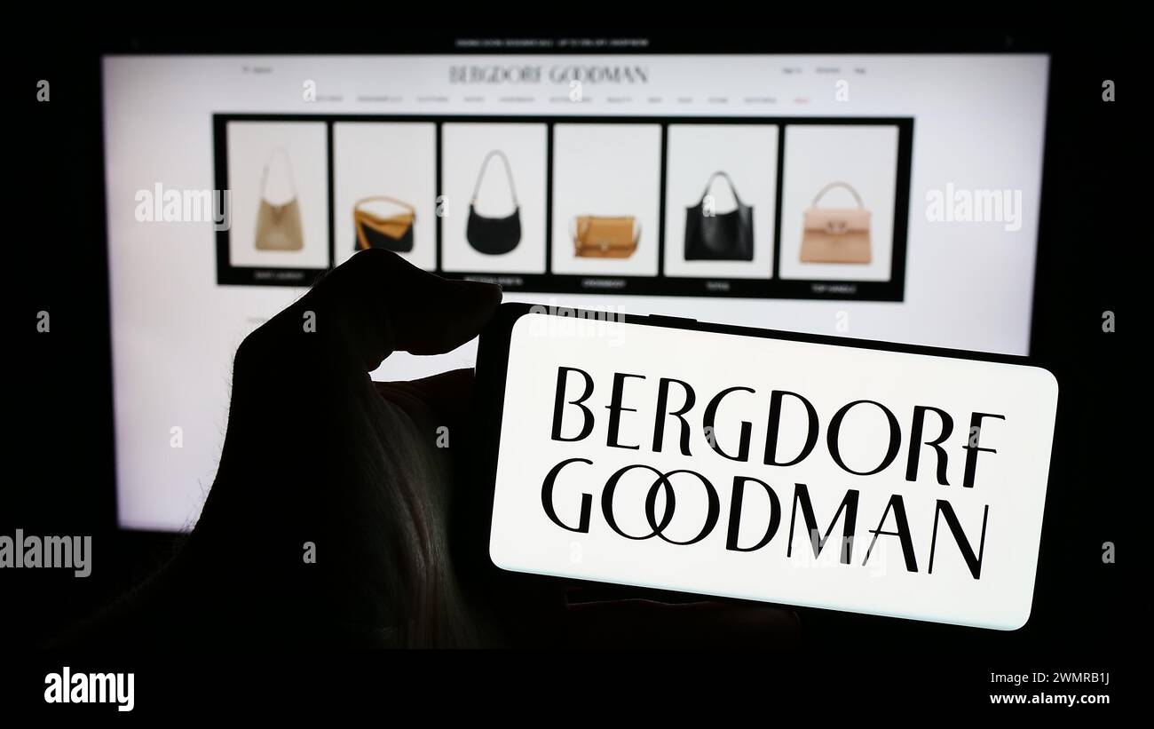 Persona che detiene un cellulare con il logo della società statunitense di grandi magazzini di lusso Bergdorf Goodman Inc. Davanti alla pagina web. Mettere a fuoco il display del telefono. Foto Stock