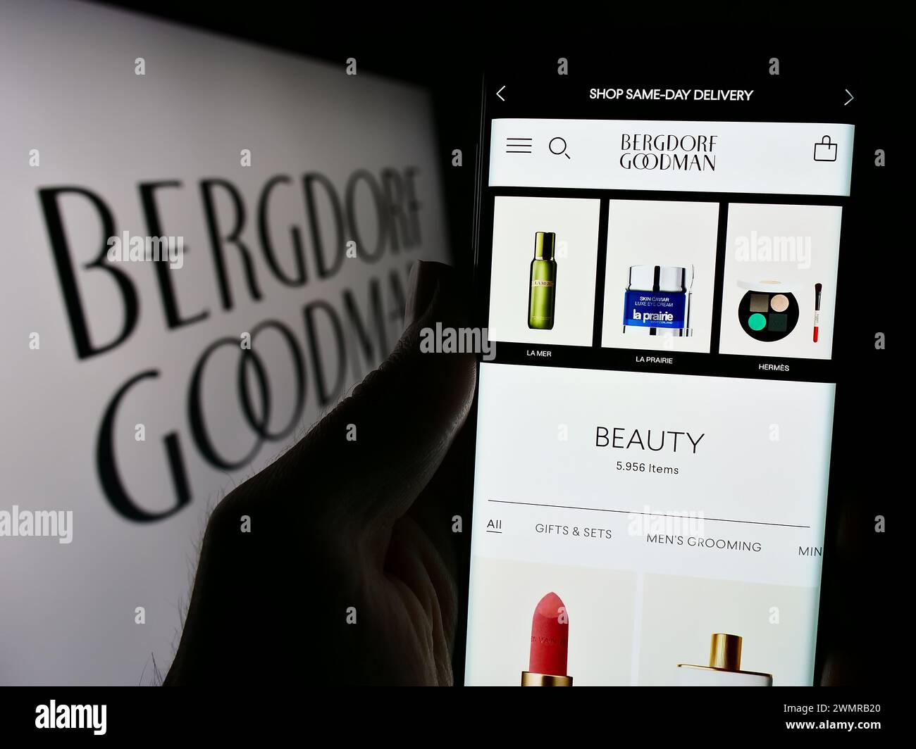 Persona che detiene un cellulare con pagina web della società di grandi magazzini di lusso degli Stati Uniti Bergdorf Goodman Inc. Con logo. Messa a fuoco al centro del display del telefono. Foto Stock