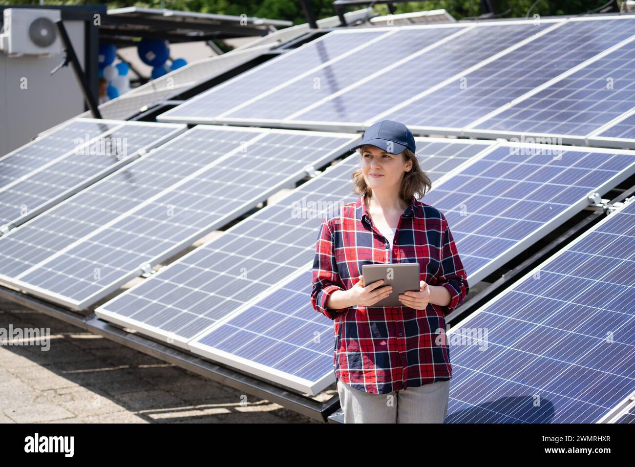 Donna con un tablet digitale accanto alla centrale a energia solare. Foto Stock