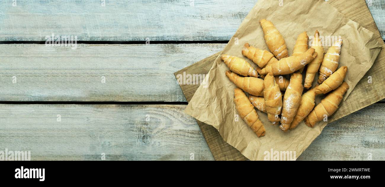 Croissant freschi su carta pergamena. Croissant croccante. Pasticceria francese. Croissant freschi sul tavolo, sullo sfondo del tavolo, con vista dall'alto e letto piatto, con Foto Stock