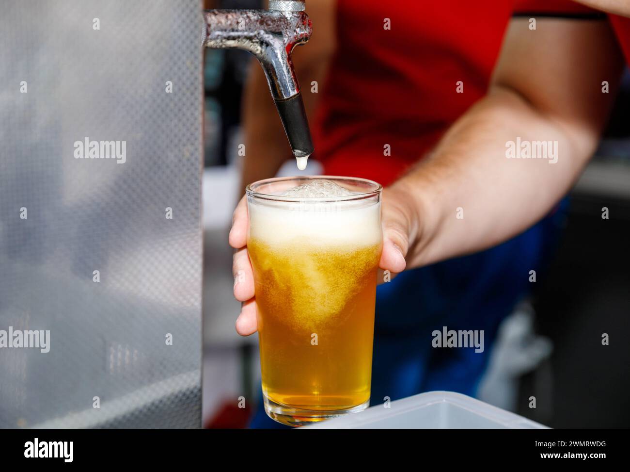 La birra viene versata da un rubinetto in un bicchiere con schiuma Foto Stock