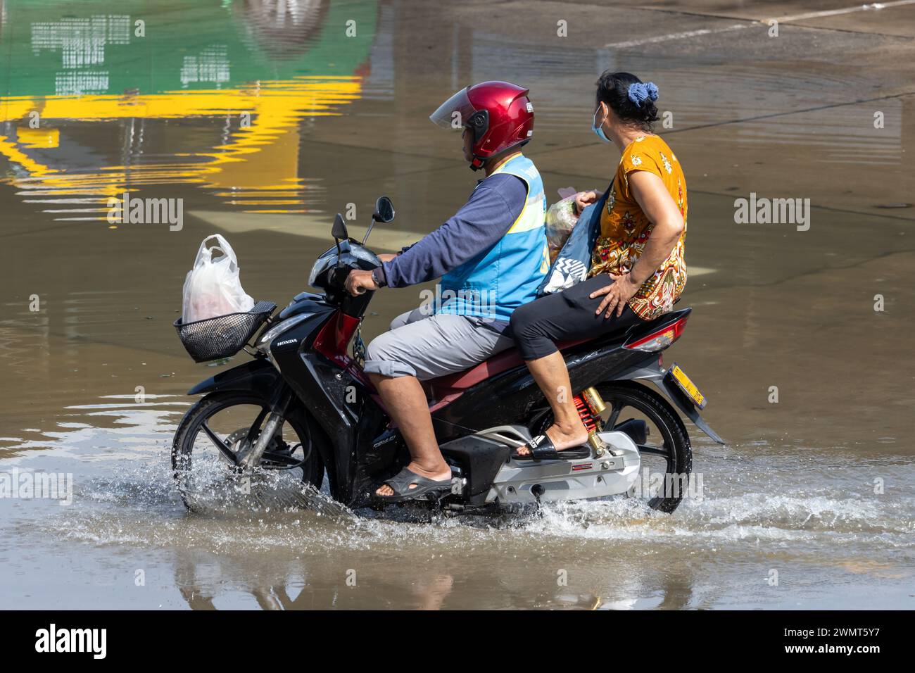SAMUT PRAKAN, THAILANDIA, novembre 30 2023, Un taxi in moto guida con un passeggero attraverso una strada allagata Foto Stock