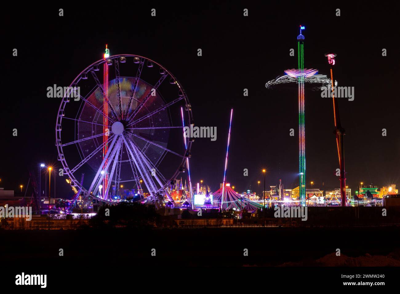 Dubai, Emirati Arabi Uniti, 11.11.20. Parco divertimenti Global Village con paesaggio notturno con ruota panoramica illuminata ed edifici del parco. Foto Stock