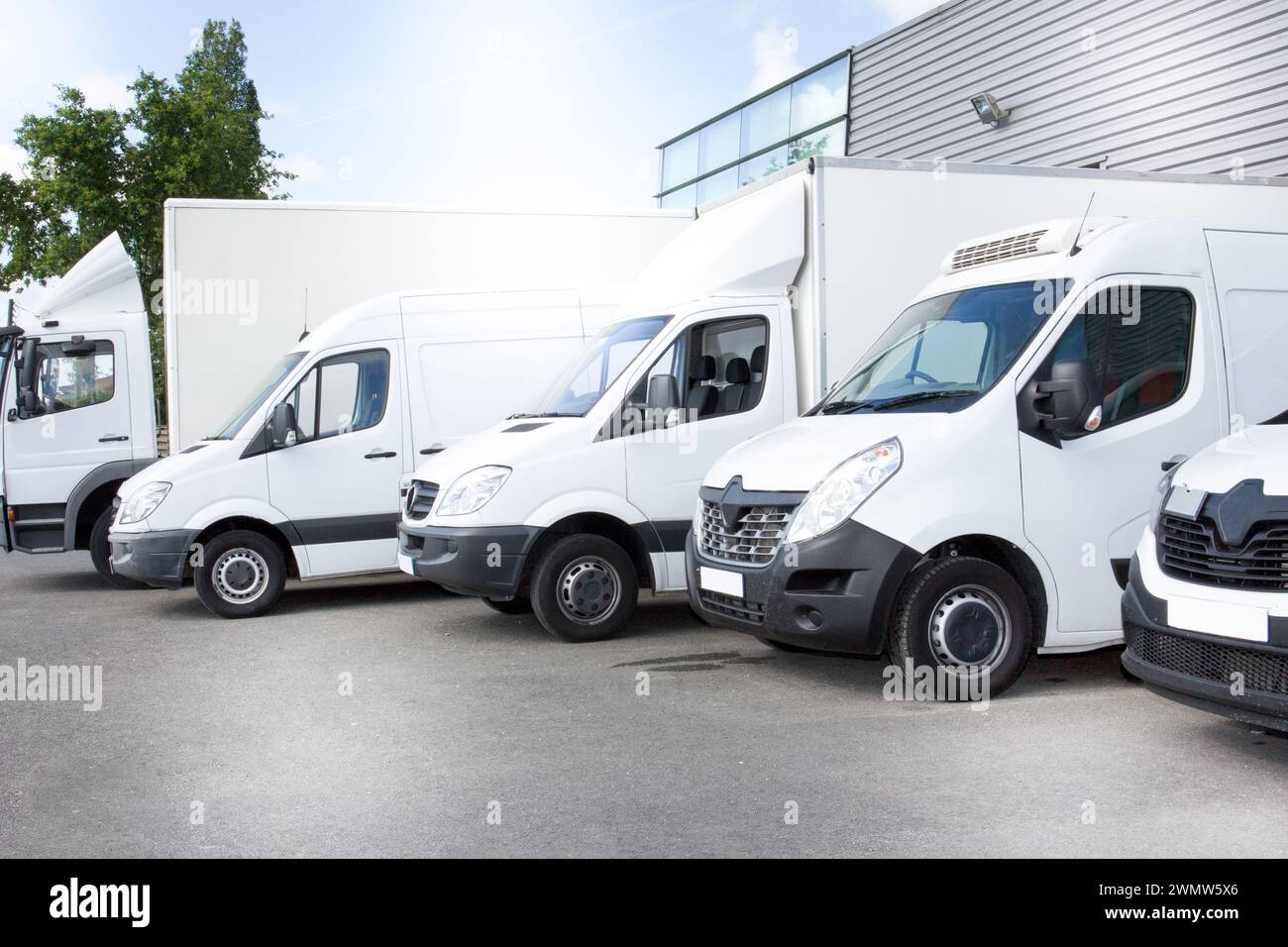 furgoni bianchi per la consegna di camion parcheggiati davanti all'ingresso di un magazzino presso il centro di distribuzione dei furgoni Foto Stock