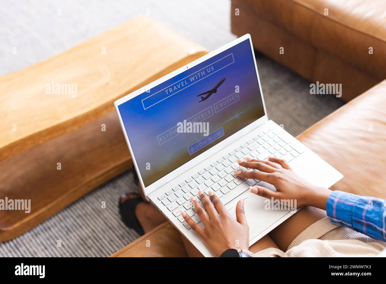 Una persona sta prenotando un viaggio online, con le dita appoggiate sulla tastiera di un notebook Foto Stock