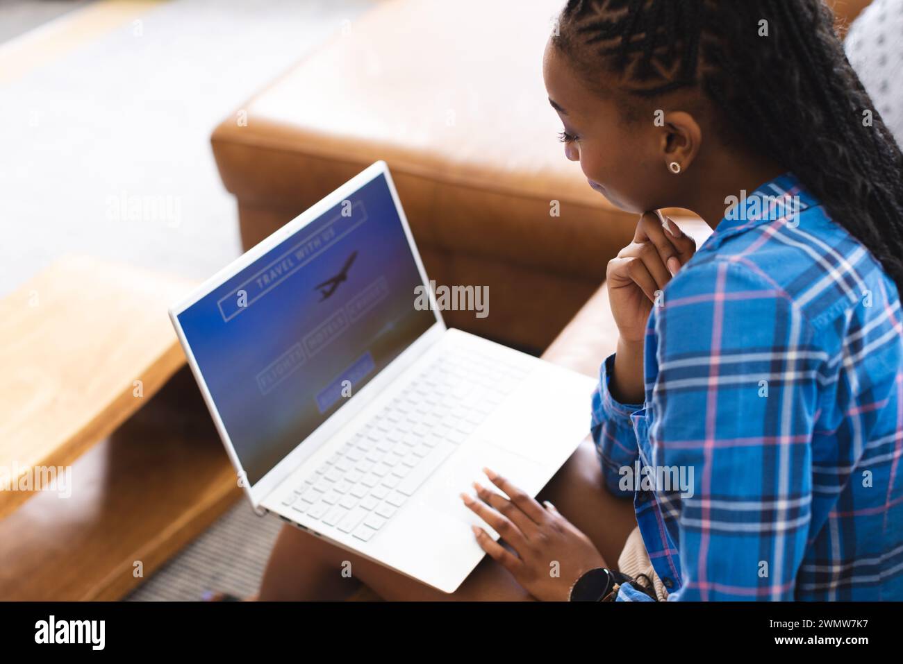 Una giovane donna afroamericana si concentra sullo schermo del suo notebook, prenotando una vacanza online Foto Stock