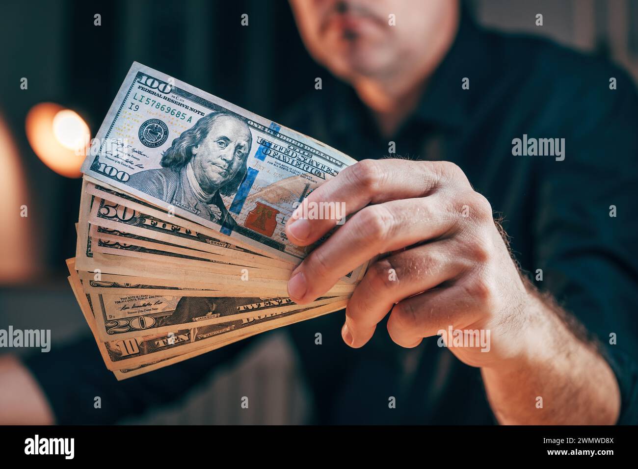 Primo piano della mano maschile con banconote in dollari, uomo d'affari che detiene denaro americano, manciata di contanti e pronto a investire in progetti imprenditoriali, seleziona Foto Stock