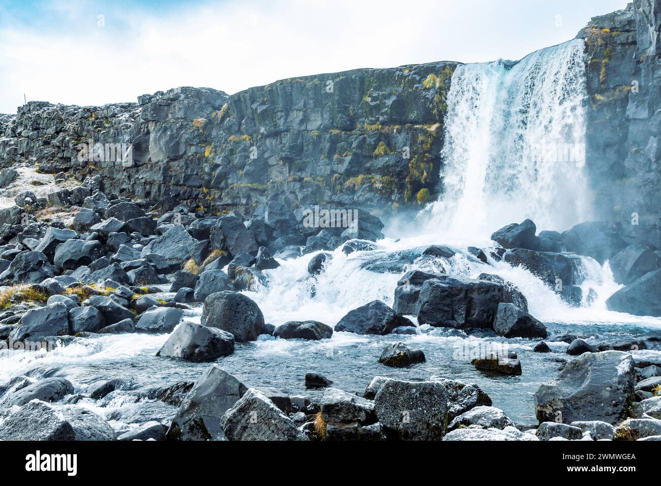 Pittoresca vista della cascata bianca di latte che scorre dalla cima della collina rocciosa e attraverso sassi aspri e taglienti in un terreno montuoso contro cl Foto Stock