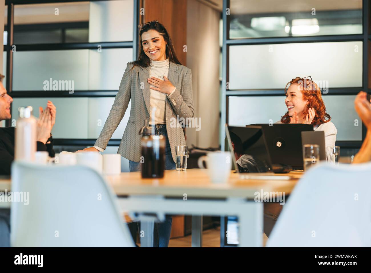 I professionisti aziendali, comprese le donne in affari, collaborano in un ufficio tecnologico. Si impegnano in una discussione vivace, applaudendo i risultati raggiunti. Il lievito Foto Stock