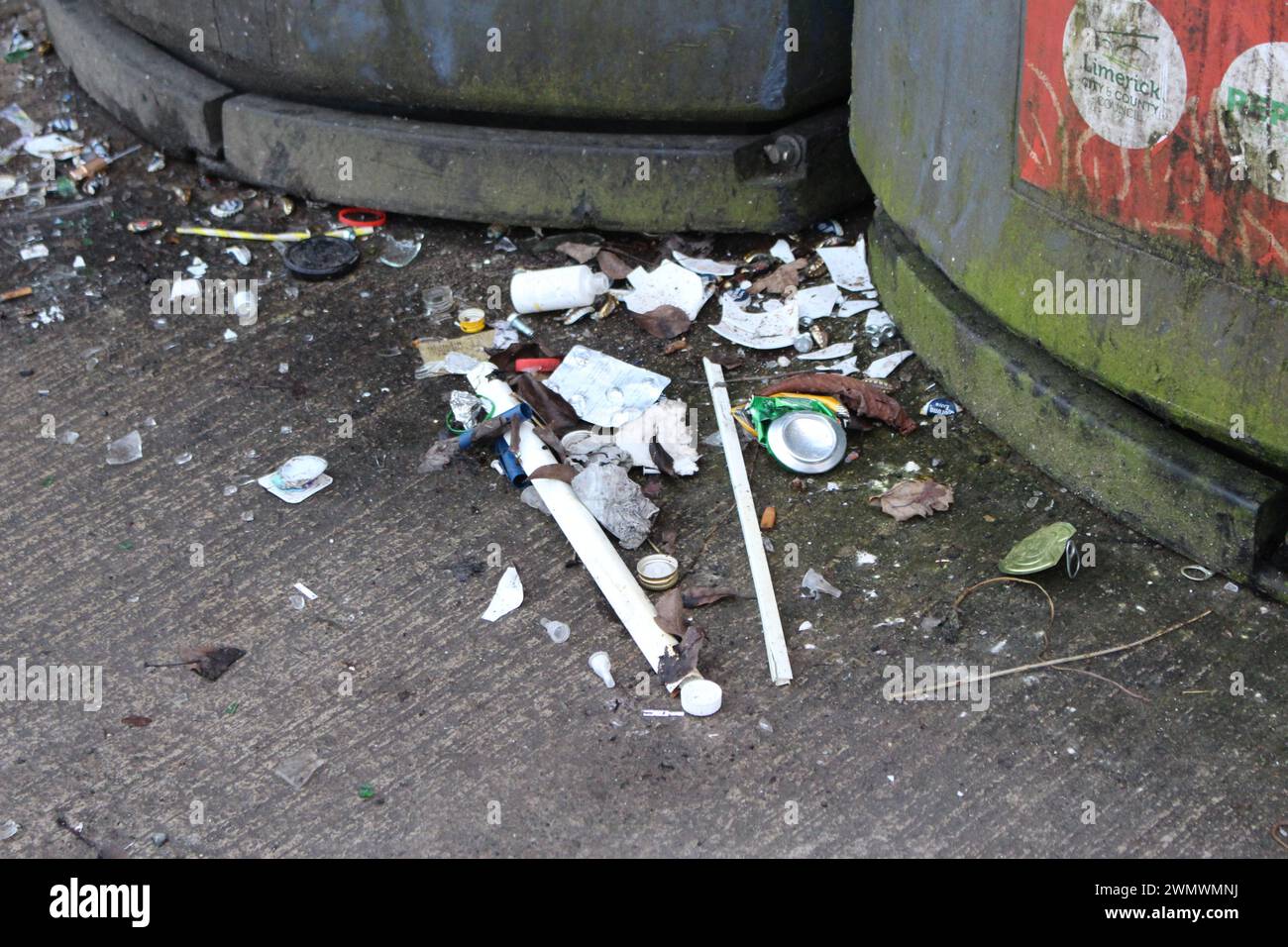 Traboccare i rifiuti all'esterno di un'area dei rifiuti municipali con contenitori per rifiuti e riciclaggio Foto Stock