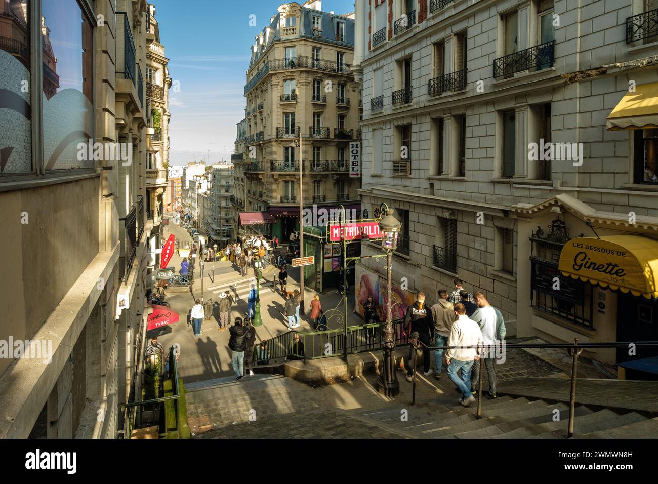 Parigi, Francia - 17 febbraio 2024: Vista dei gradini che conducono ad una pittoresca stazione della metropolitana e ad un tipico caffè francese nella zona di Montmartre a Parigi Foto Stock