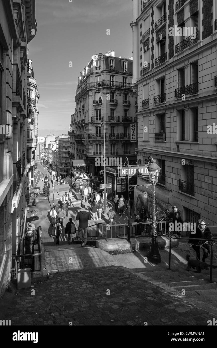 Parigi, Francia - 17 febbraio 2024: Vista dei gradini che conducono ad una pittoresca stazione della metropolitana e ad un tipico caffè francese nella zona di Montmartre a Parigi Foto Stock