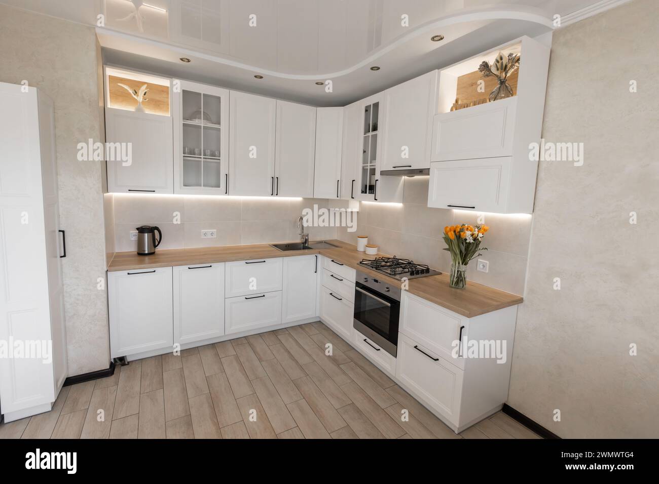 un moderno interno di cucina bianca con piano di lavoro in legno Foto Stock