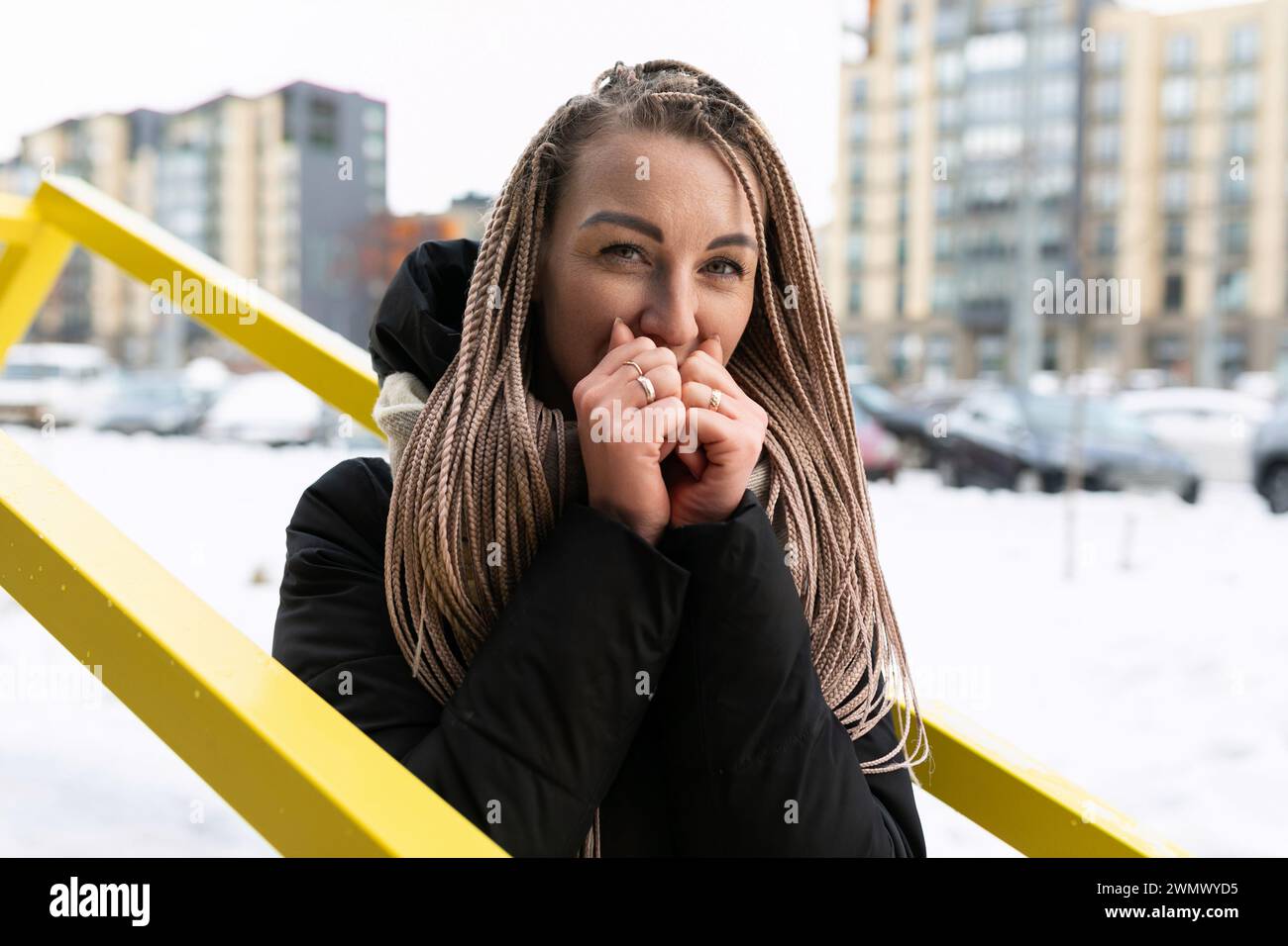 Una donna sorridente con dreadlock biondi cammina per la città con la neve in inverno Foto Stock