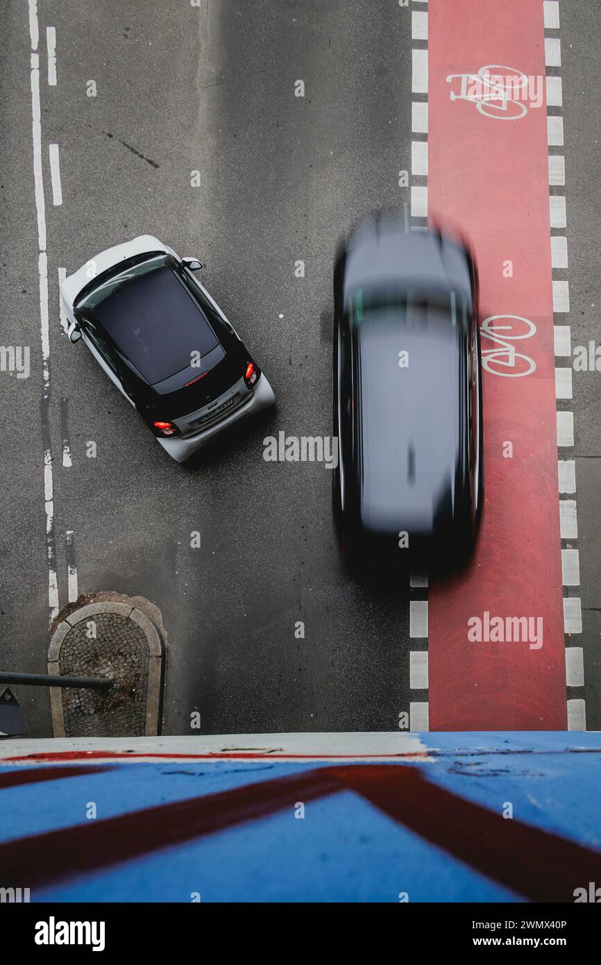 Un'auto sorpassa una persona che gira a sinistra sulla pista ciclabile segnalata a Berlino, 27 febbraio 2024. Foto Stock
