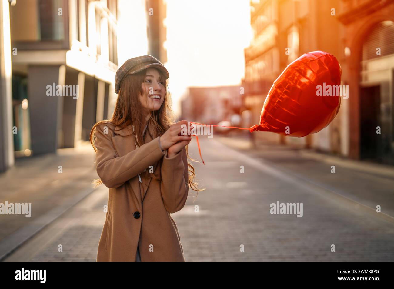 Giovane donna felice con una mongolfiera a forma di cuore che si innamora, che trascorre una giornata di divertimento, passeggiando per la città inglese la primavera è nell'aria Lifestyle, Tourism, V Foto Stock