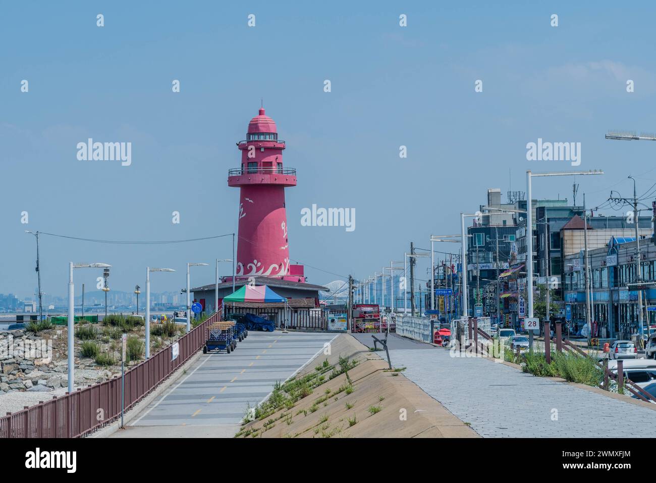 Faro rosso di Oido sul molo accanto alla strada principale fiancheggiata da aziende della Corea del Sud Foto Stock
