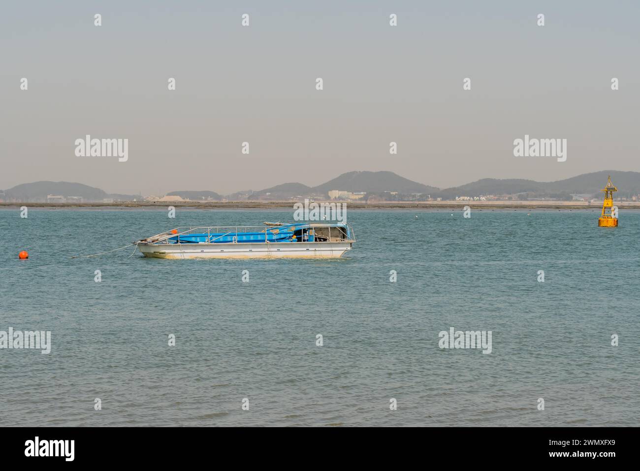 Barca da pesca con fondo piatto ancorata nel porto vicino alla boa gialla a Pyeongtaek, Corea del Sud Foto Stock