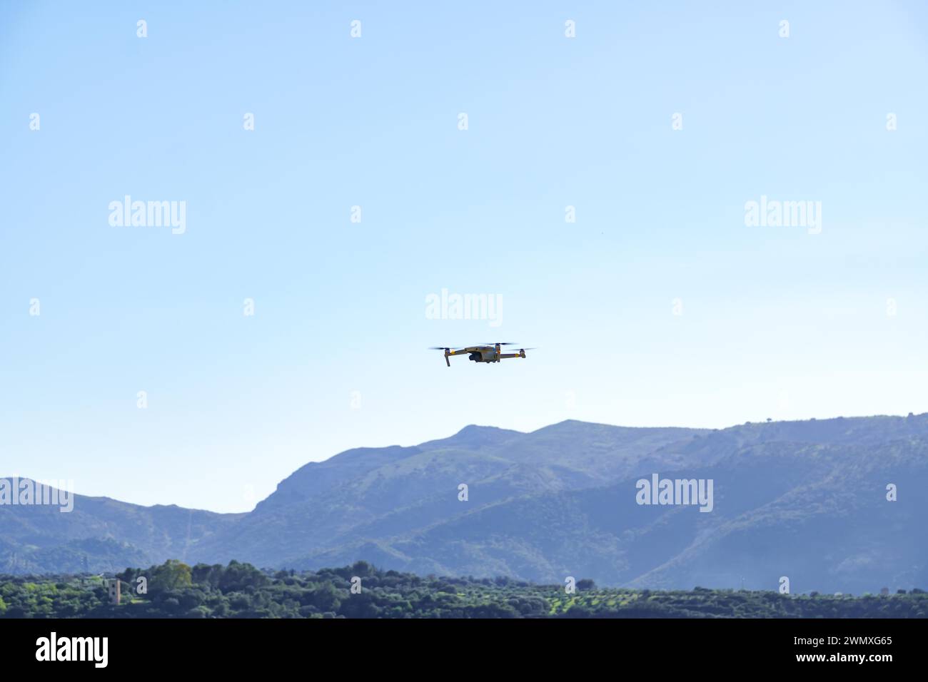 Drone in volo che registra un paesaggio di montagna verde con un cielo blu Foto Stock