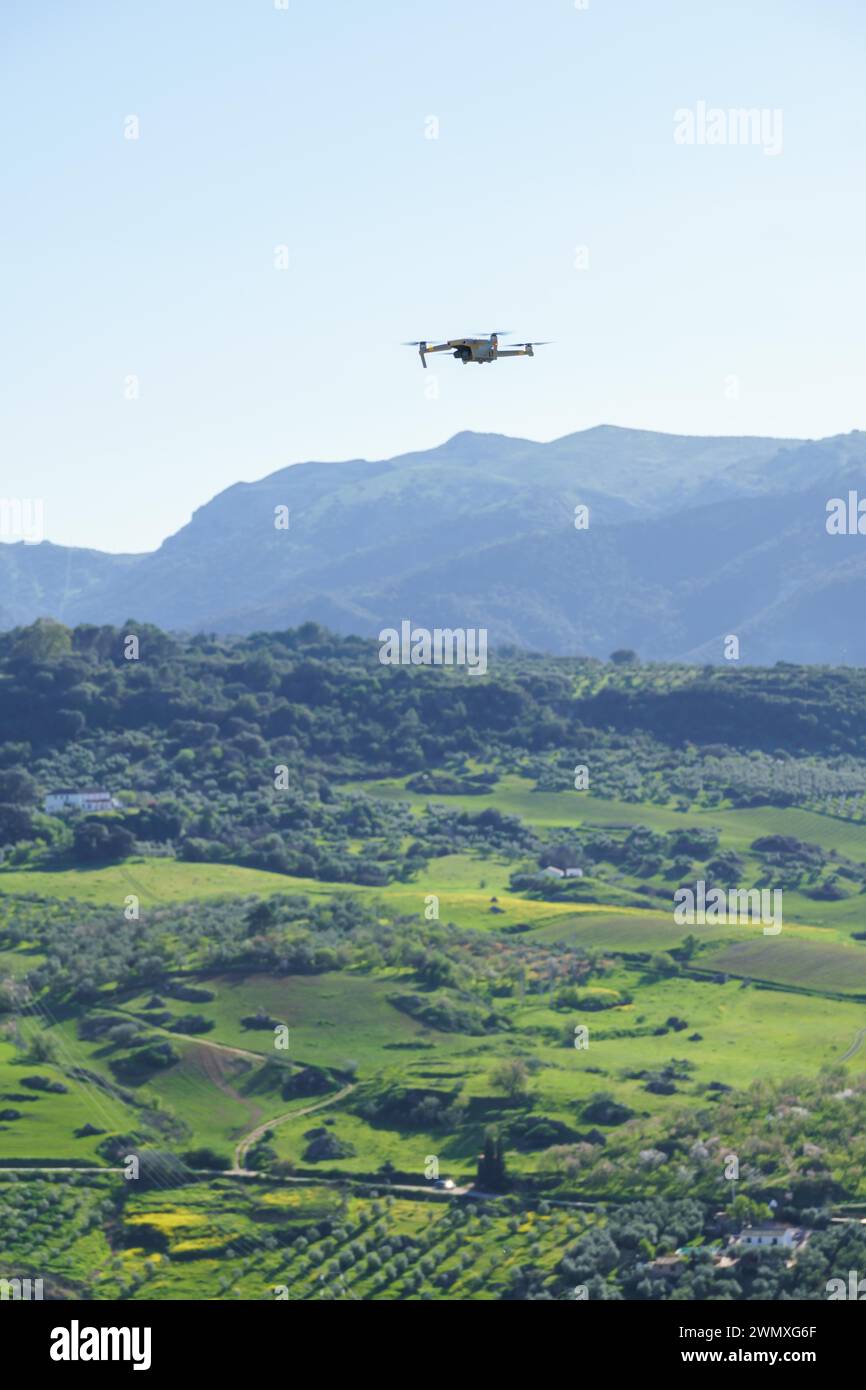 Drone in volo che registra un paesaggio di montagna verde con un cielo blu Foto Stock