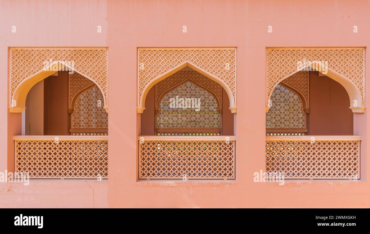 Tre archi simili in una parete color terracotta con complessi motivi geometrici nell'architettura islamica, Oman Foto Stock