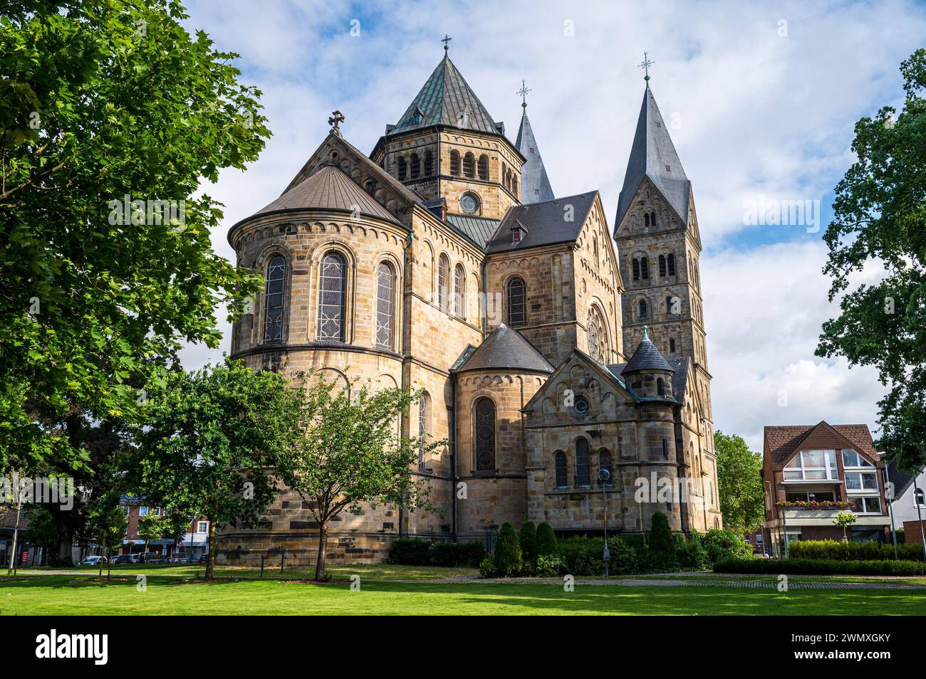 Maestosa cattedrale gotica con merlature, inondata di luce solare, contro un cielo nuvoloso, Basilica di Sant'Anna, Neuenkirchen, Renania settentrionale-Vestfalia Foto Stock