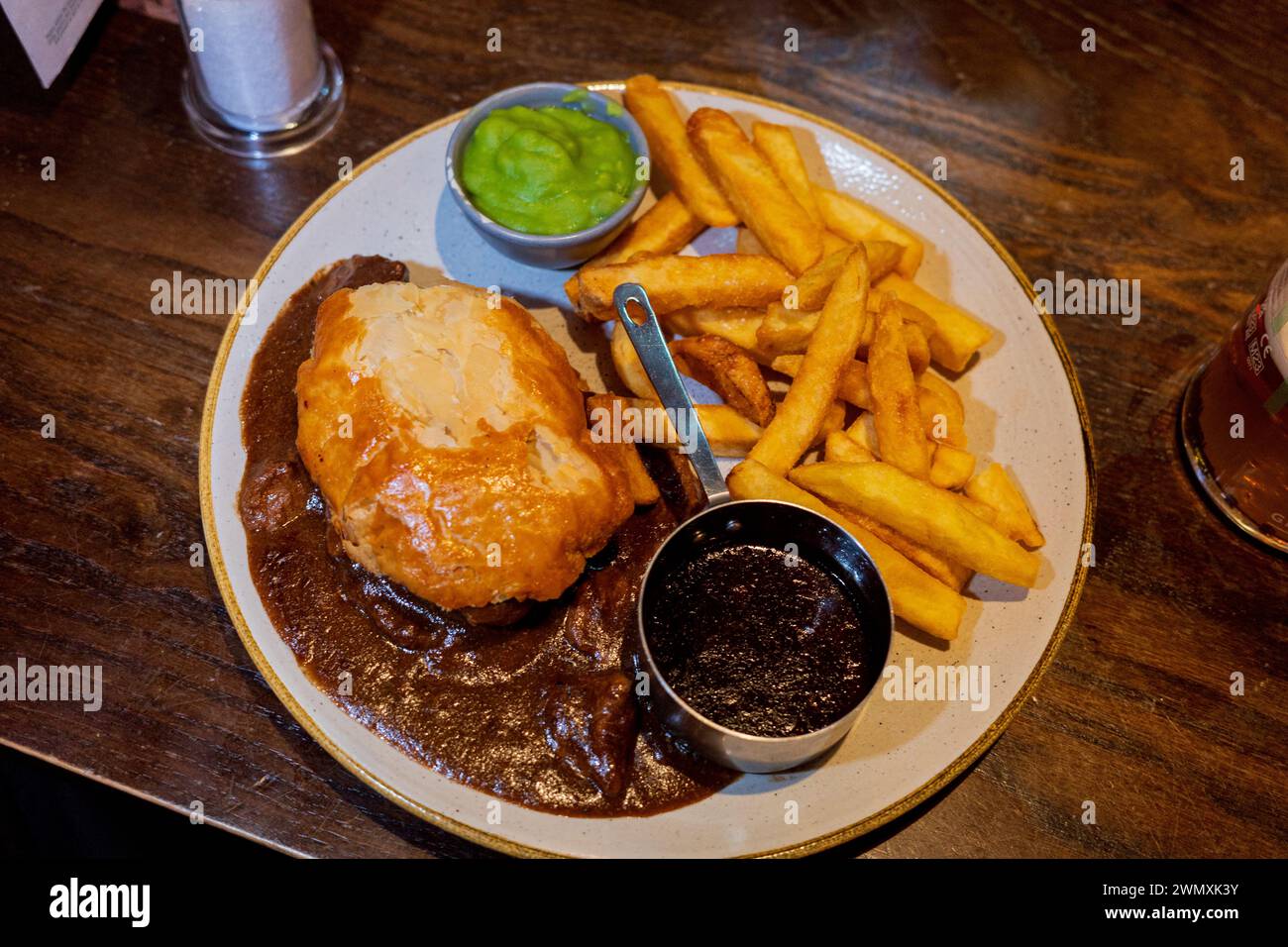 Bistecca di Edimburgo e torta alla birra e una pinta in un pub scozzese con patatine, salsa e piselli moschi Foto Stock