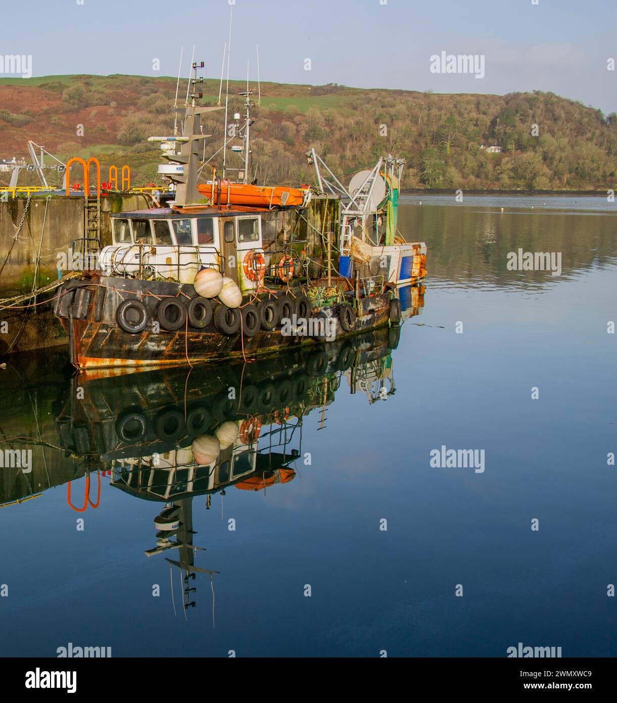 Vecchio rimorchiatore con riflessi in acque calme e piatte Foto Stock