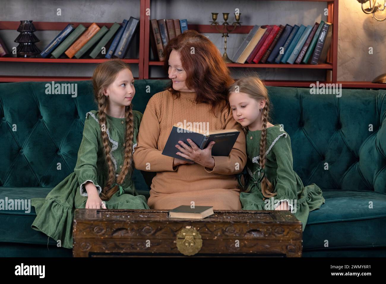Felice nonna e nipoti leggono libri insieme e si divertono a casa Foto Stock