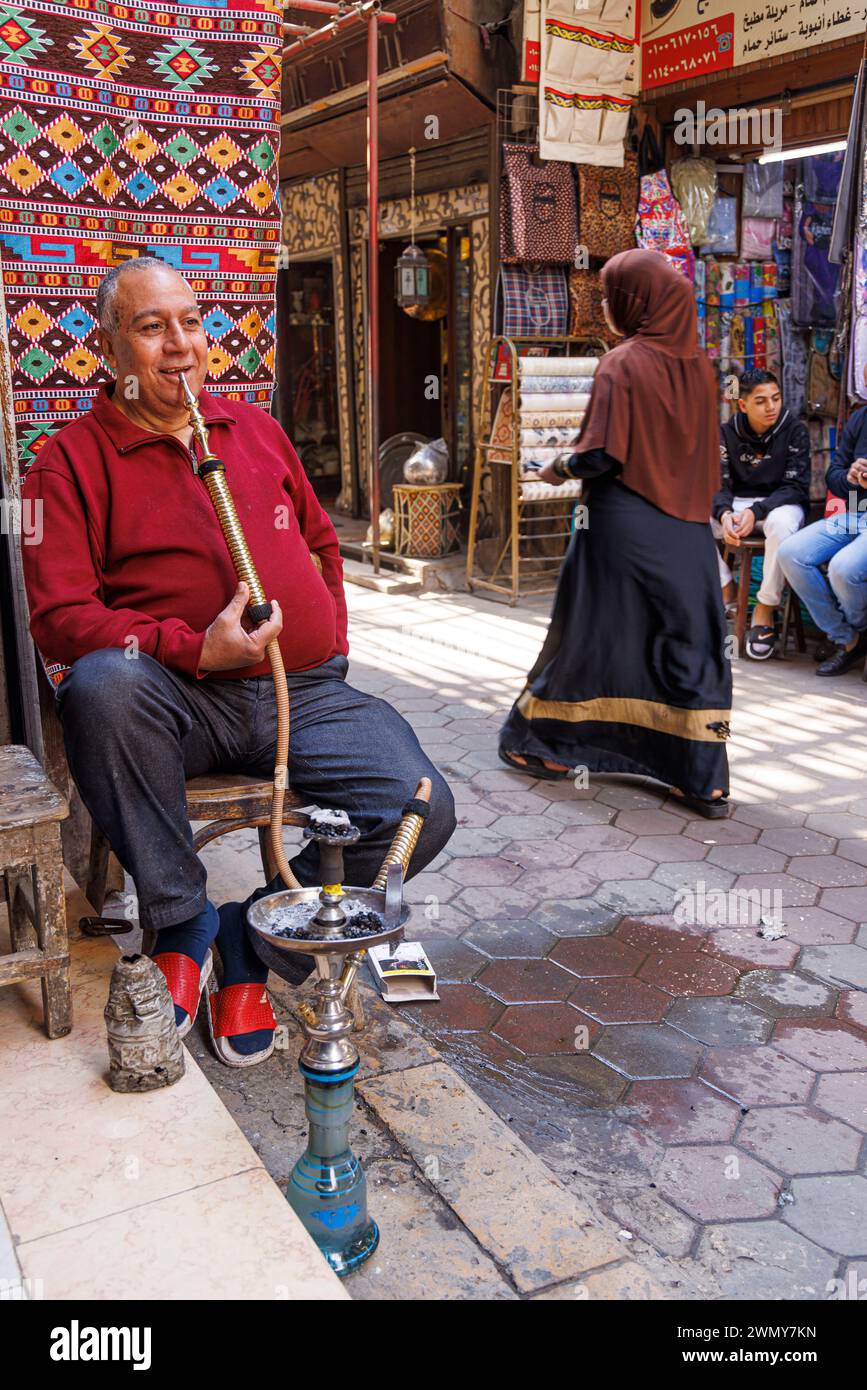 Egitto, Cairo, il Cairo storico patrimonio dell'umanità dell'UNESCO, mercato El Khiamiah (o tentmakers), uomo che fuma un narghilè Foto Stock
