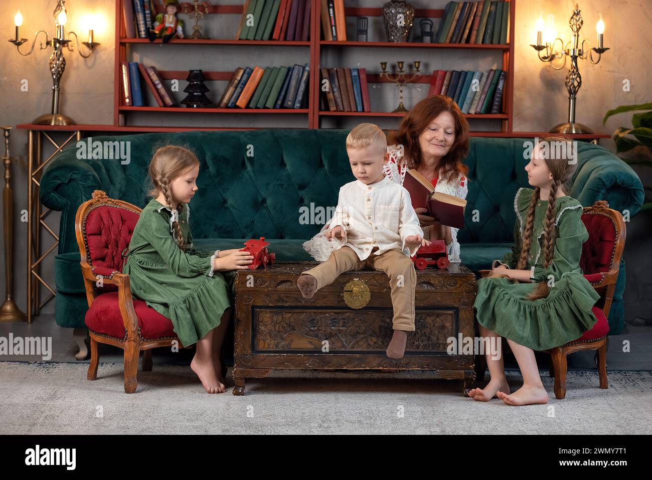 Felice nonna e nipoti leggono libri insieme e si divertono a casa Foto Stock
