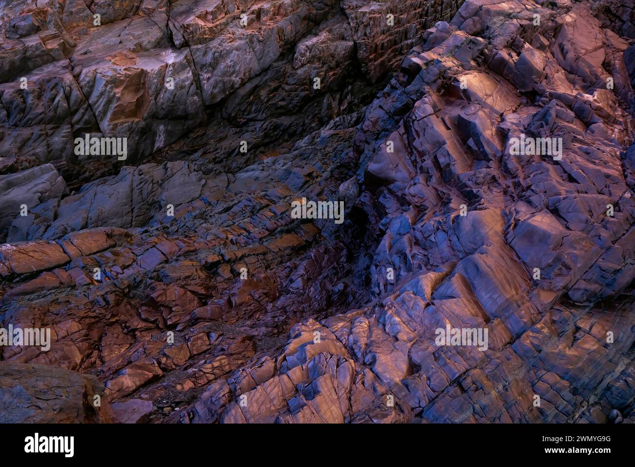 Foto ravvicinata che cattura i dettagli intricati e i colori vivaci delle rocce ricche di ferro e dei batteri del biofilm lungo la vecchia spiaggia delle miniere di Llumeres nelle Asturie. Foto Stock