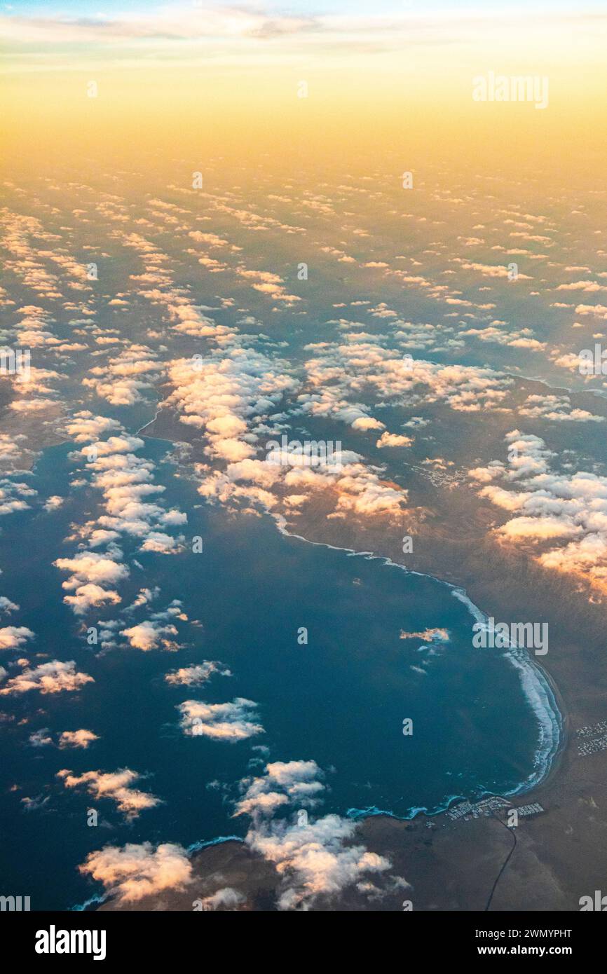 Caleta de Famara e la Bahia de Penedo sull'isola delle Canarie di Lanzarote, in Spagna, viste da un aereo di passaggio verso il tramonto. Foto Stock