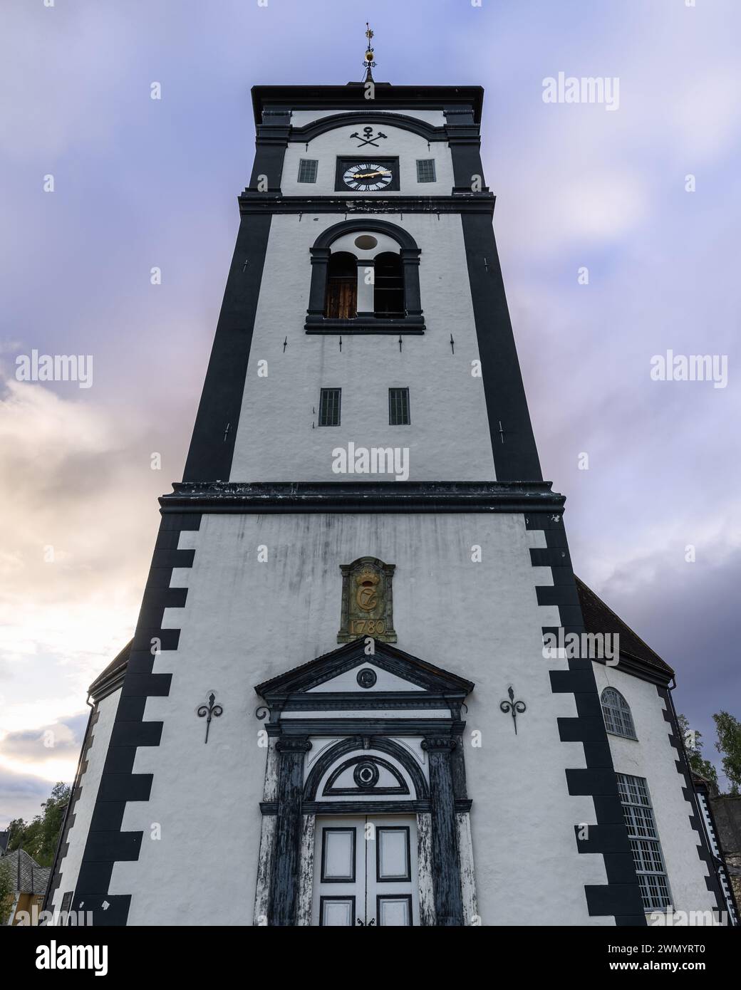 La chiesa di Roros svetta nel cielo, con la sua classica faccia a orologio e l'ingresso ornato, un punto focale contro il cielo crepuscolo in questo sito patrimonio norvegese Foto Stock