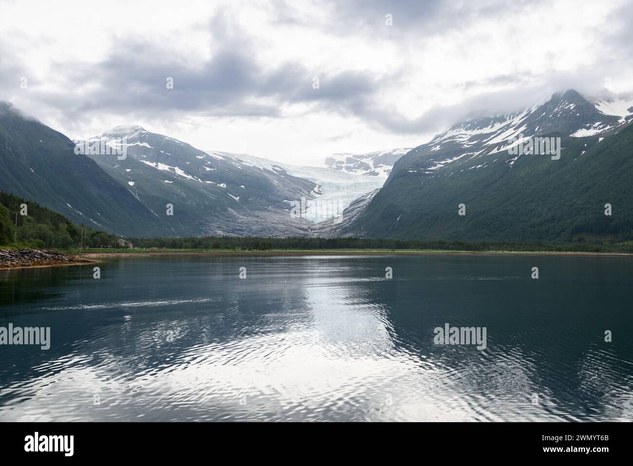 La grandezza del ghiacciaio Svartisen si riflette nelle acque tranquille del fiordo, un sereno riflesso del paesaggio dinamico e della bellezza glaciale della Norvegia Foto Stock