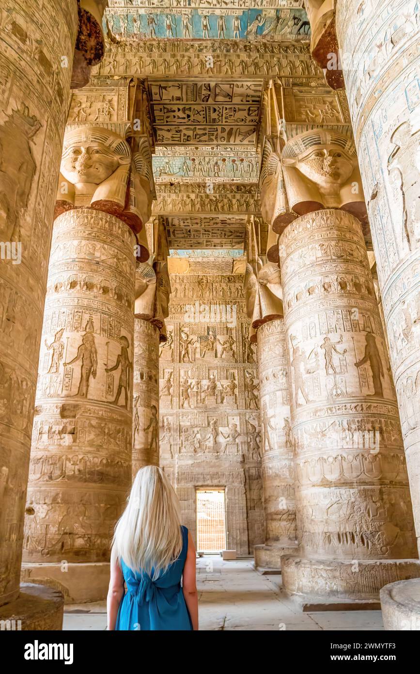 Dendera, Egitto - Una donna dai capelli biondi guarda l'interno della sala ipostilio nel Tempio di Dendera. Foto Stock