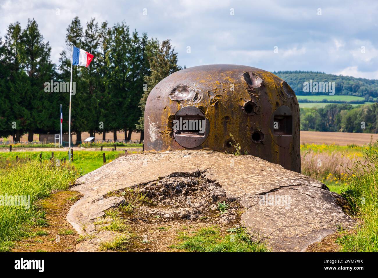 Torretta corazzata che mostra l'impatto di un proiettile sull'ouvrage de la Ferté a Villy, in Francia, parte della linea Maginot, con una bandiera francese che sventola in lontananza. Foto Stock