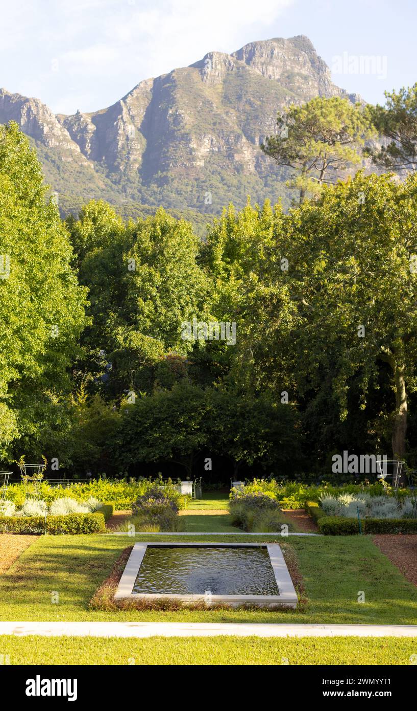 Un giardino ben curato con giochi d'acqua è adagiato sullo sfondo di una montagna con spazio fotocopie Foto Stock