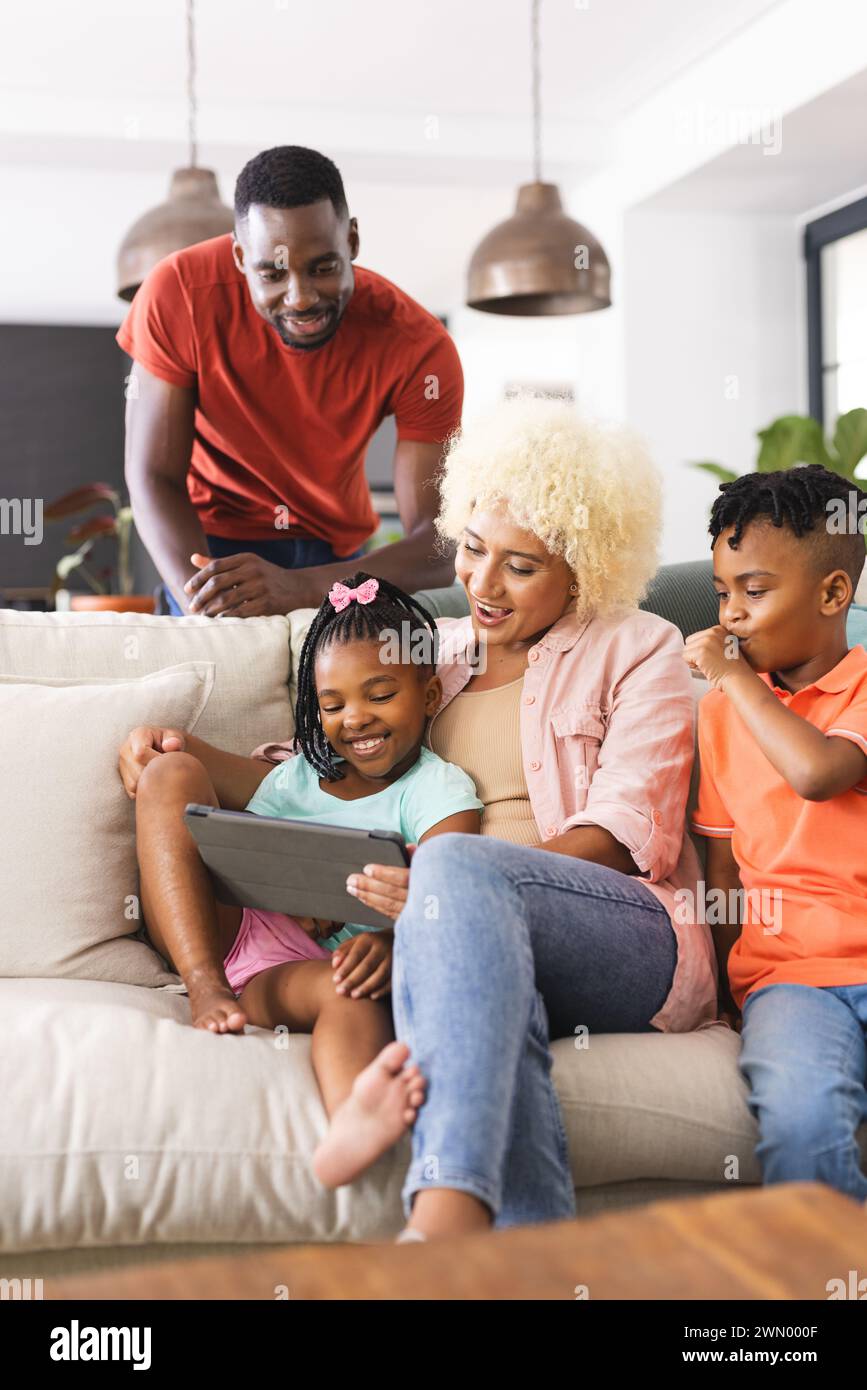 La famiglia ama passare il tempo con la tecnologia su un comodo divano. Foto Stock