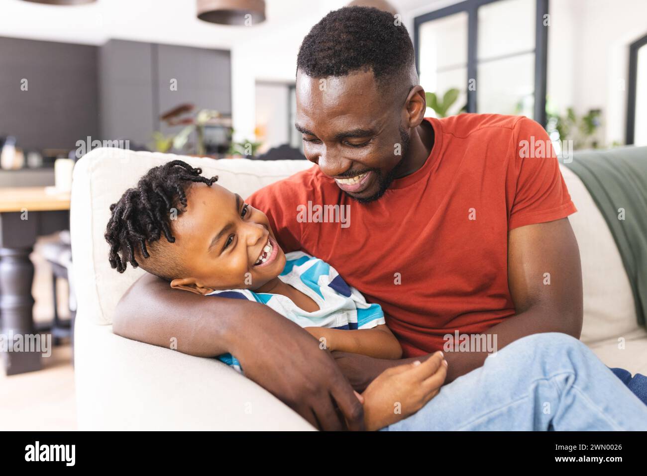 Il padre afroamericano condivide un momento di gioia con suo figlio, entrambi sorridenti calorosamente Foto Stock