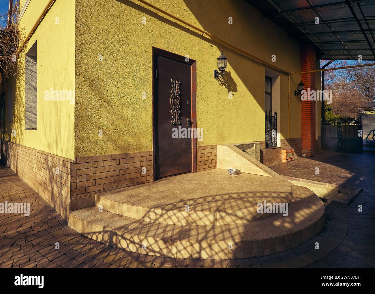 Il cortile è lastricato di piastrelle e ci sono gradini di portico alla porta d'ingresso della casa. Odessa, Ucraina. Foto Stock
