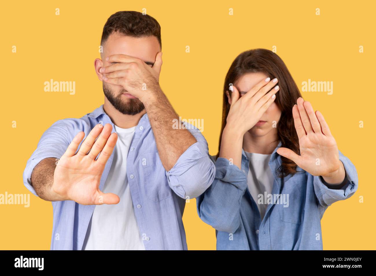 Uomo e donna che coprono gli occhi, mostrando un gesto di arresto della mano Foto Stock