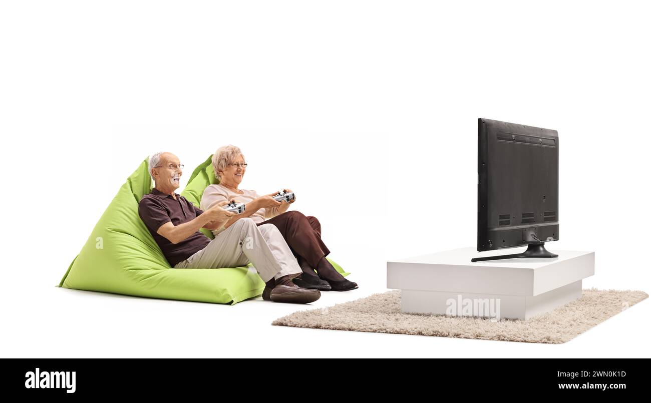 Coppia anziana che gioca ai videogiochi in tv e si siede su beanbags isolati su sfondo bianco Foto Stock