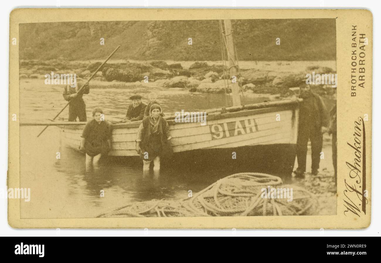 La carte de visite vittoriana originale (biglietto da visita o CDV) di una famiglia di pescatori che lancia una barca da pesca (registrata come 91 AH) ad Auchmithie, luogo di nascita del famoso Arbroath Smokie - eglefino affumicato, barche più piccole come questa venivano utilizzate per la pesca di granchi e aragoste. Dal fotografo scozzese W J Anckorn di Arbroath (studi presso Brothock Bridge e Brothock Bank), Scozia, Regno Unito circa 1880 Foto Stock