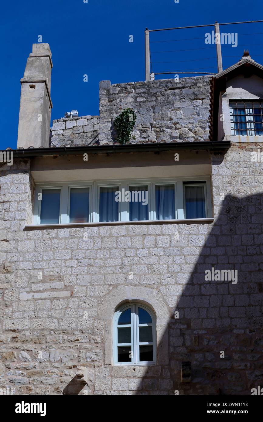 Vista sulla strada dei piani superiori di edifici residenziali medievali in pietra con finestre pittoresche in uno stretto vicolo della città vecchia di Spalato, Croazia. Foto Stock