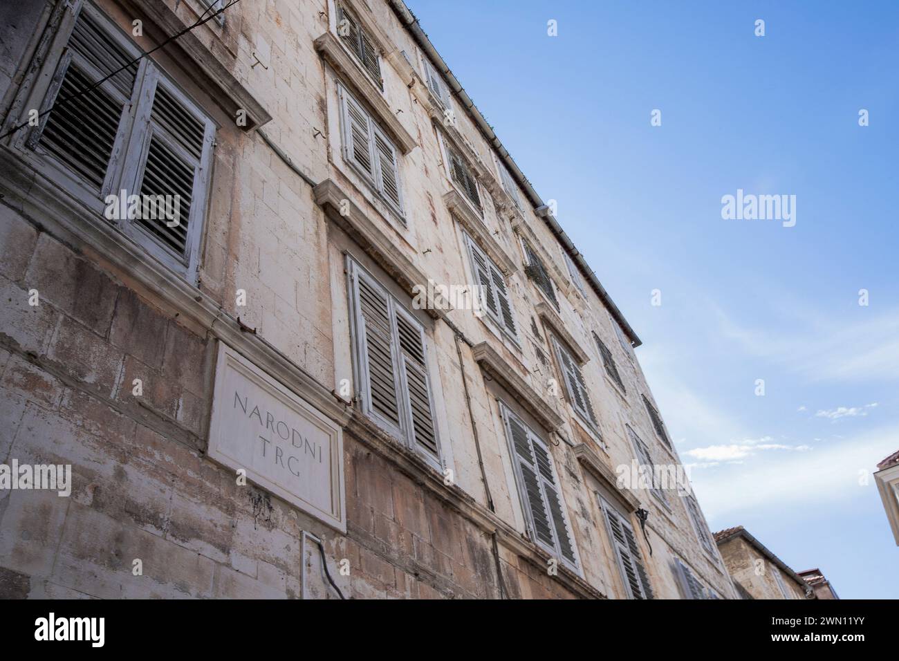 Vista sulla strada dei piani superiori di edifici residenziali medievali in pietra con finestre pittoresche in uno stretto vicolo della città vecchia di Spalato, Croazia. Foto Stock