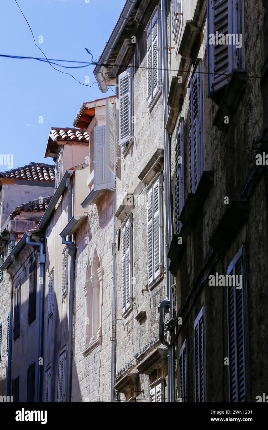 Vista sulla strada dei piani superiori di edifici residenziali medievali in pietra con finestre pittoresche in uno stretto vicolo della città vecchia di Spalato, Croazia. Foto Stock