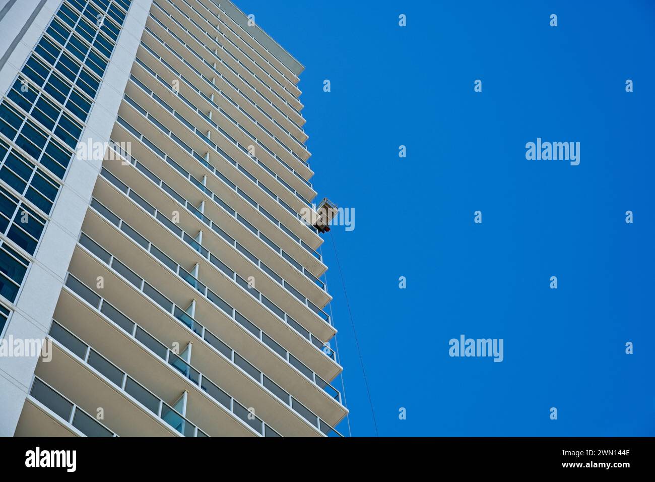 Il carrello per il lavaggio delle finestre è appeso alla torre del condominio Foto Stock