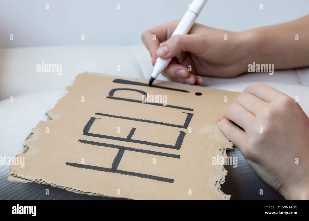 Una richiesta di aiuto. Una donna scrive la parola aiuto su un foglio di cartone Foto Stock