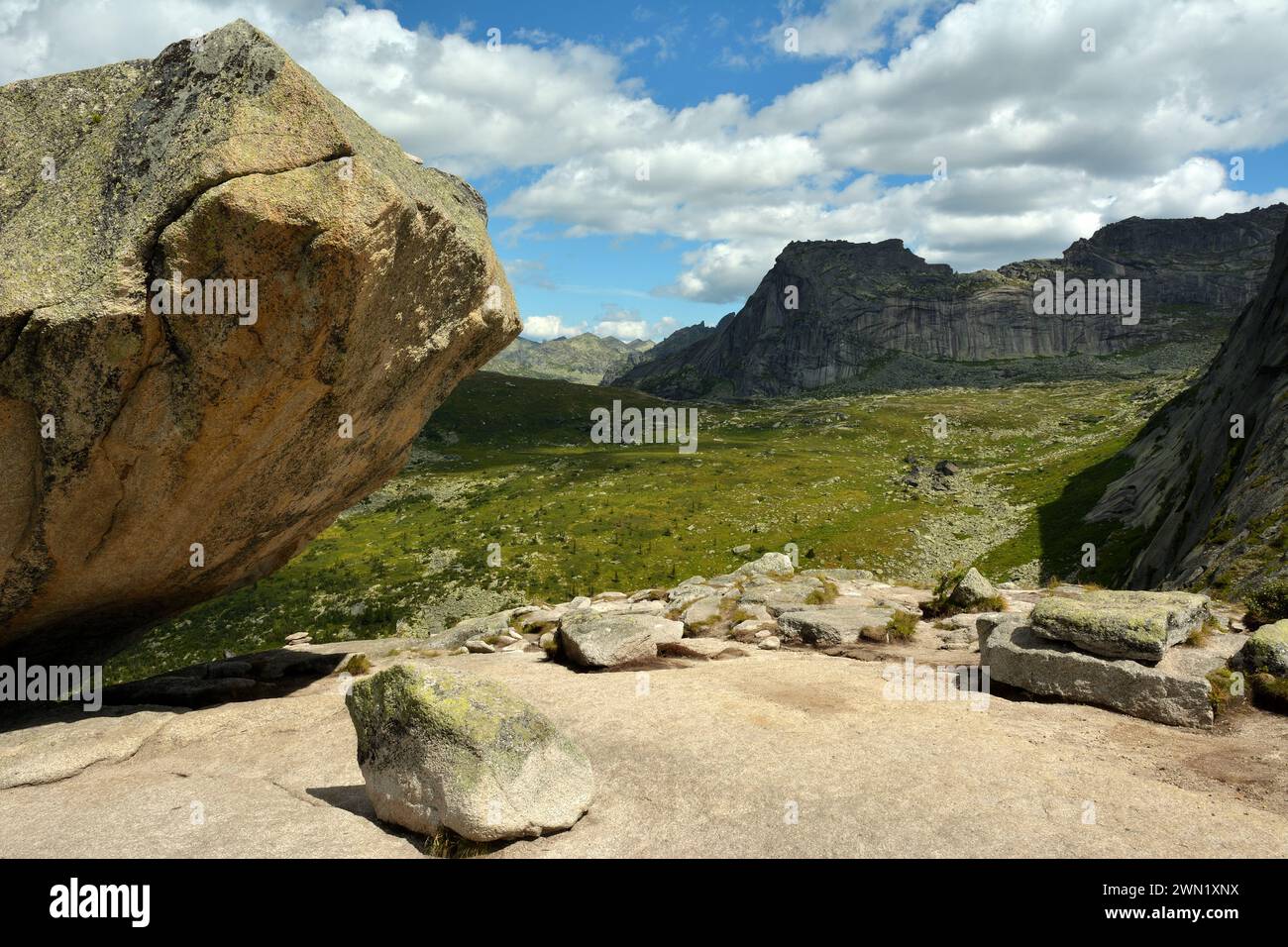 Un frammento di un'enorme pietra sulla cima di una montagna che si affaccia su una massa rocciosa sotto forma di persona che mente. Monte Sleeping Sayan, territorio di Krasnoyarsk, si Foto Stock